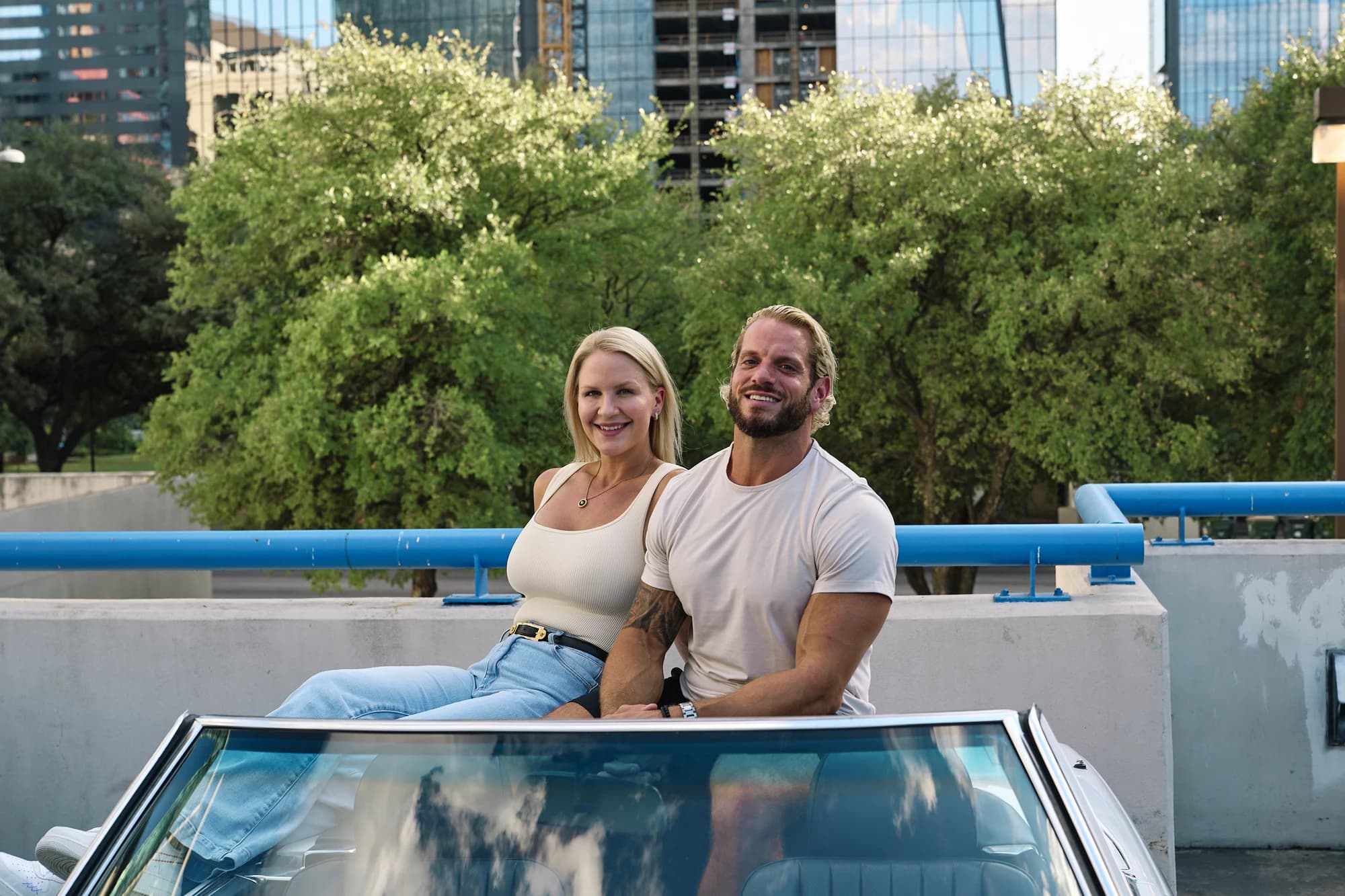 Jarred and Katelyn Curcio on a convertible with the Austin skyline behind them