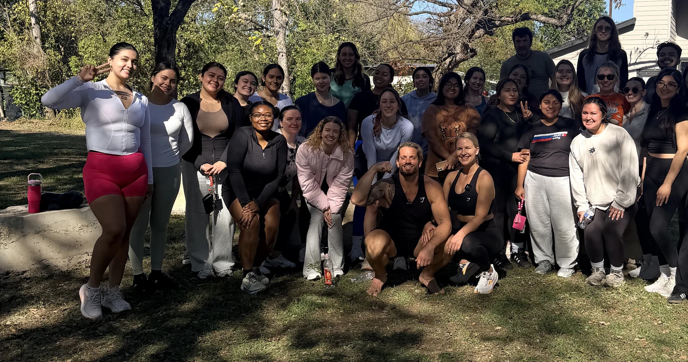 Jarred and Katelyn Curcio smiling with a large group of nursing students under the trees in Austin, Texas