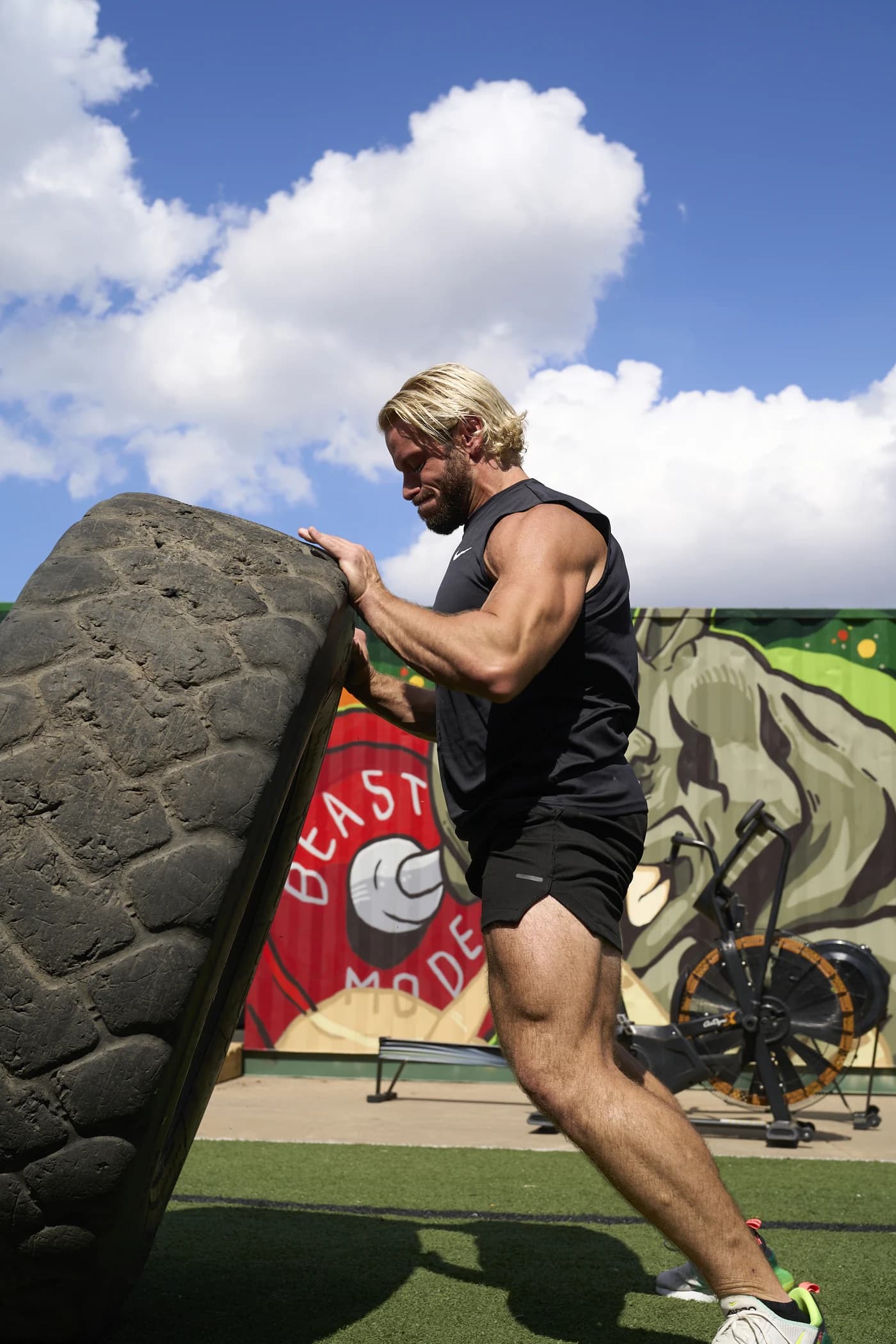 Jarred Curcio flipping a heavy tire in front of the BEAST MODE mural in Austin, Texas