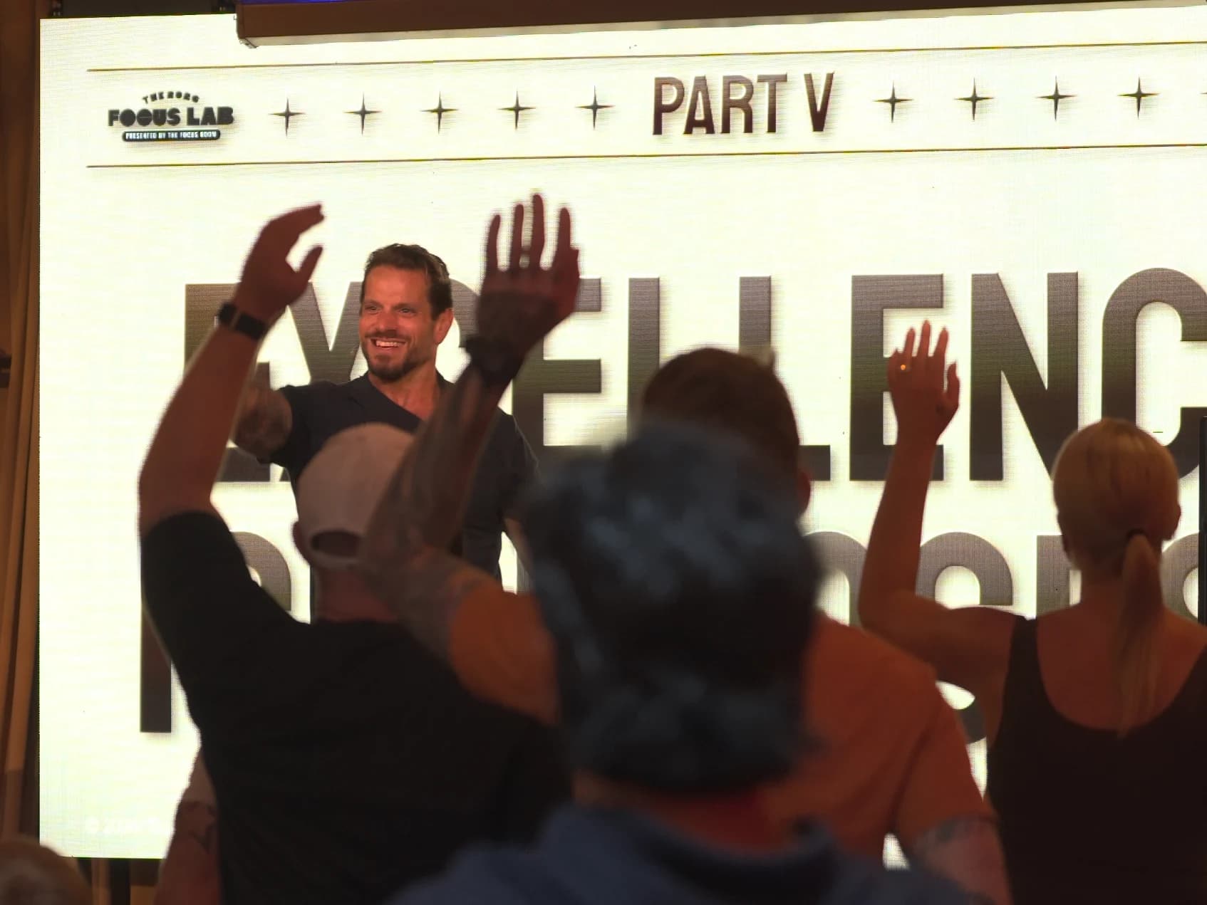Jarred Curcio smiling on stage at The Focus Lab with the room's hands in the air during the Morning MAN-UP in Austin, Texas