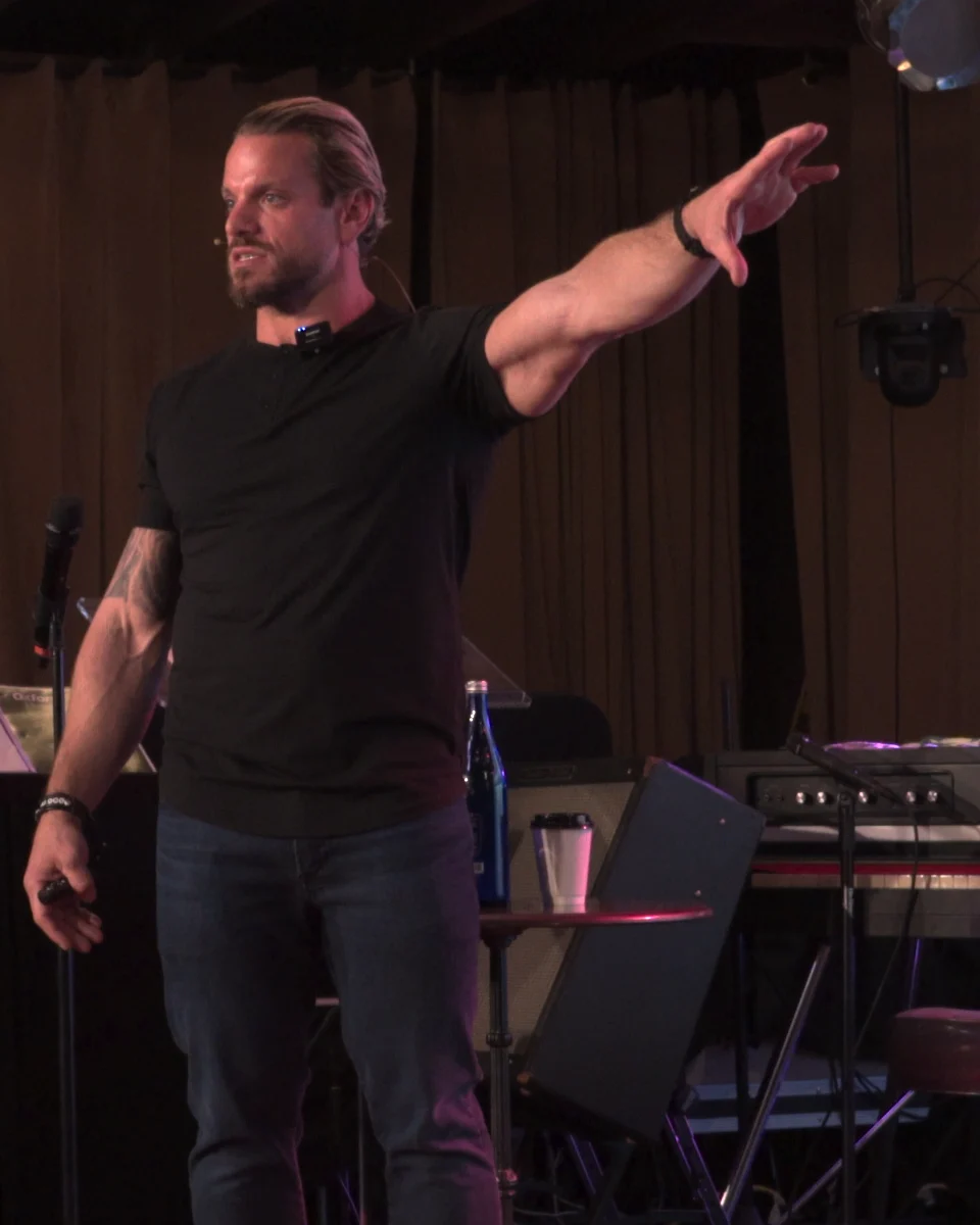 Jarred Curcio on stage at The Focus Lab with his hand extended to the side in Austin, Texas