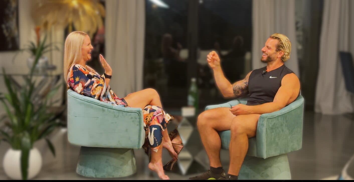 Jarred and Katelyn Curcio laughing across from each other in green velvet chairs while recording the Genius at Work podcast